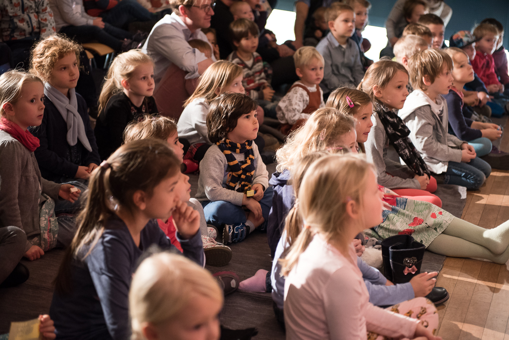 Viele Kinder sitzen gespannt auf dem Boden und lauschen der Musik und dem Gesang von Marko Simsa im Haus der Musik